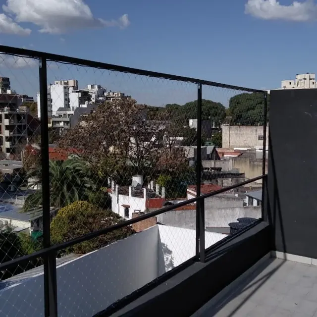 Balcón con red y vista a los árboles.