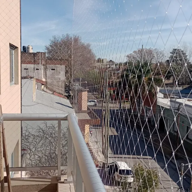 Balcón con baranda blanca y red transparente hasta arriba.