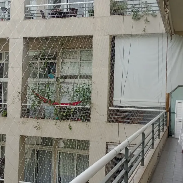 Balcón de departamento con red sobre la baranda.