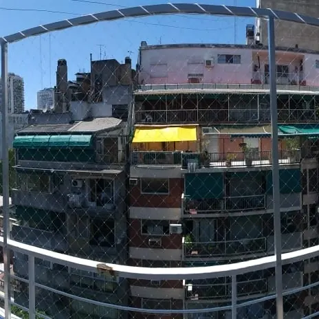 Balcón con red frente a edificios de la ciudad.