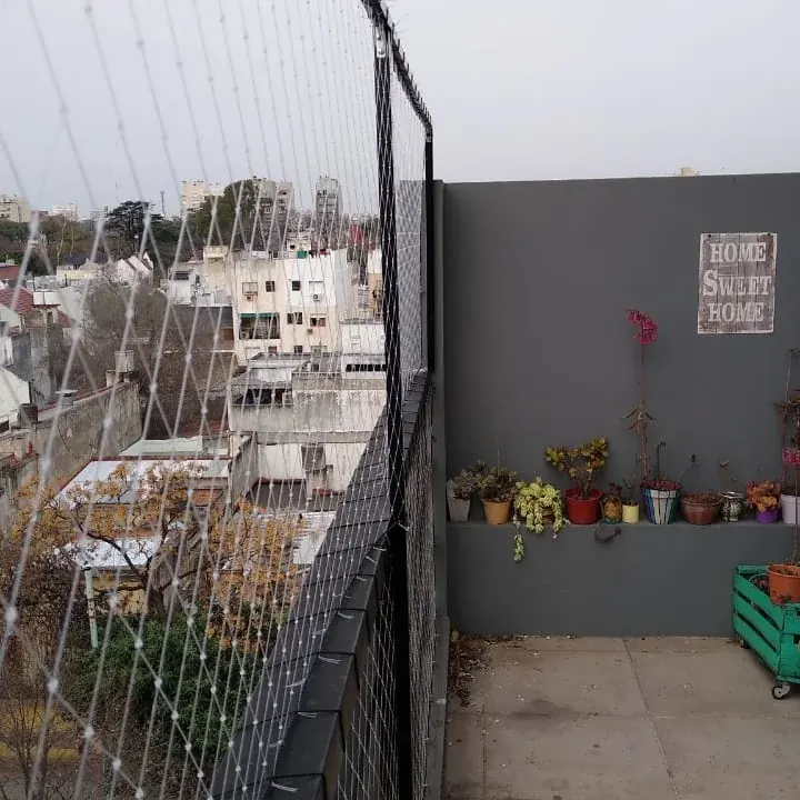 Balcón con plantas cerrado con red de protección hasta el techo.