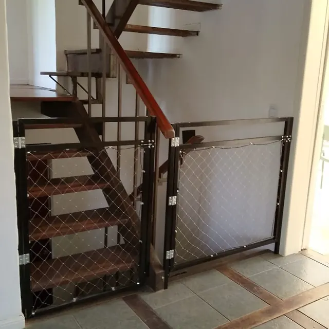 Escalera interior con baranda y puerta metálica con red.