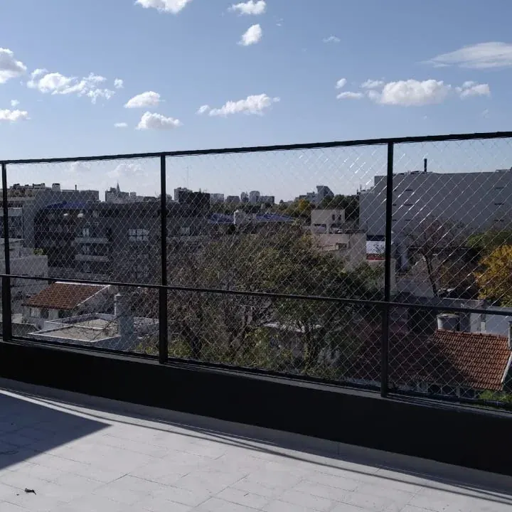 Terraza con red de protección transparente frente al cielo de la ciudad.