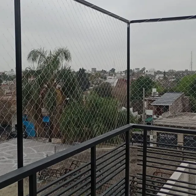 Baranda de terraza con red tensada y vista a los techos del barrio.